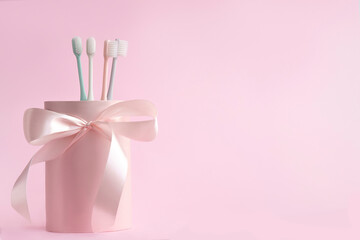 Pink packaging gift box with toothbrushes on pink background .