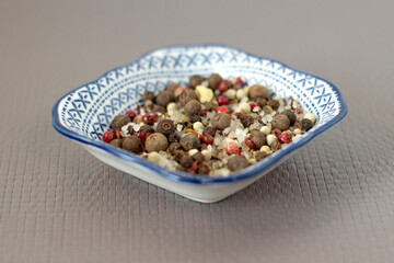 Sea salt and spices in small blue plate with pattern, chilli, Bay leaf, close-up, on light grey linen background