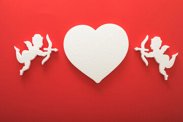 Flying cupid silhouette with hearts, gifts, happy Valentine's Day banners, paper art style. Amour on red paper