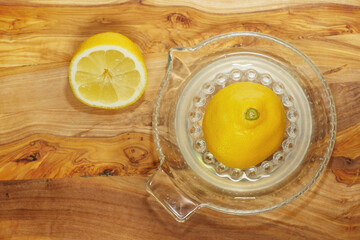 Fresh half lemon on glass juicer on a wooden board. Juice is on the bottom of jar. Close up. Top down view
