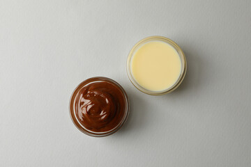 Bowls with condensed milk on gray background