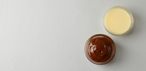 Bowls with condensed milk on gray background