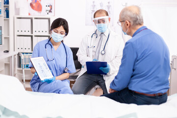 Healthcare physician explaining human anatomy to senior man showing tablet pc in time of covid...