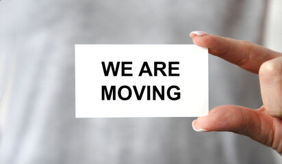 The girl keeps a business card with We Are Moving tacts in front of her.