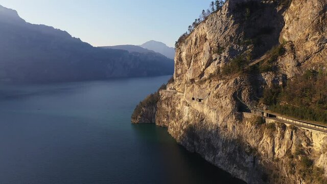 Aerial footage of the dramatic coastal road along the Lake Lucerne in late afternoon on a sunny day in Canton Uri in Central Switzerland