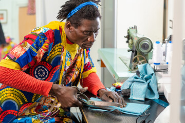 african tailor from senegal at work in his workshop, handcrafted production of european fashion clothes with african wax fabrics, concept of diversity and integration, new small socialbusiness - obrazy, fototapety, plakaty
