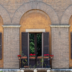 Rome Italy, vintage building balcony arched window decorated with colorful flowers