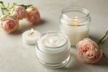 Scented candles, cosmetic cream and roses on white table