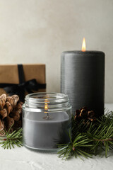 Scented candles, gift box and pine branches with cones on white table