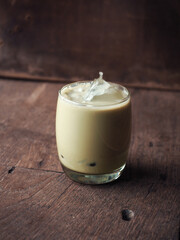glass of iced green tea latte on wooden table