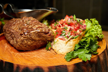 Grilled Veal steak with tomato salsa on a wooden plate. Close-up, selective focus