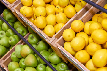Lemons and green apples in wooden boxes on store shelves