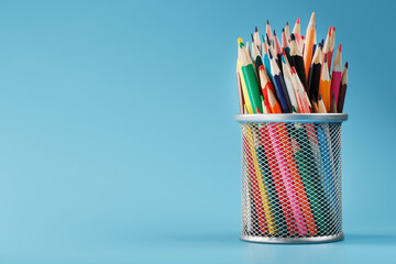 Colorful pencils in a metal jar on a blue background.
