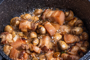 Cooking spicy pork stew with mushrooms in oriental style in a saucepan with spices, hot peppers and green onions - top view, close-up