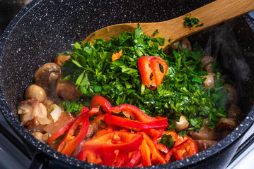 Cooking spicy pork stew with mushrooms in oriental style in a saucepan with spices, hot peppers and green onions - top view, close-up