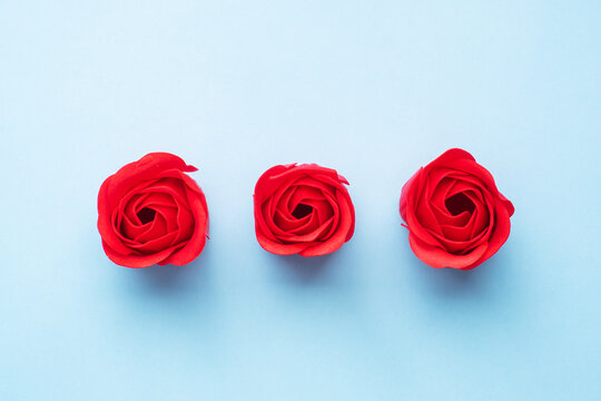 Handmade soap in the shape of a rose, red rose flower on a blue background. Top view, minimalist, copy space.