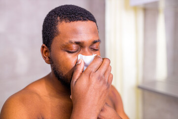 Fototapeta premium african american man snot symptom feeling bad stay at home looking at mirrror in bathroom