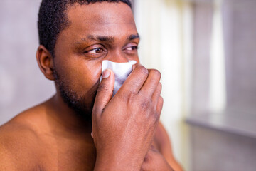 african american man snot symptom feeling bad stay at home looking at mirrror in bathroom