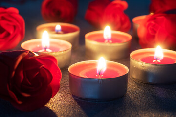 Fototapeta na wymiar Red roses and burning candles, close up, romantic greeting card. concept of Valentine's Day.