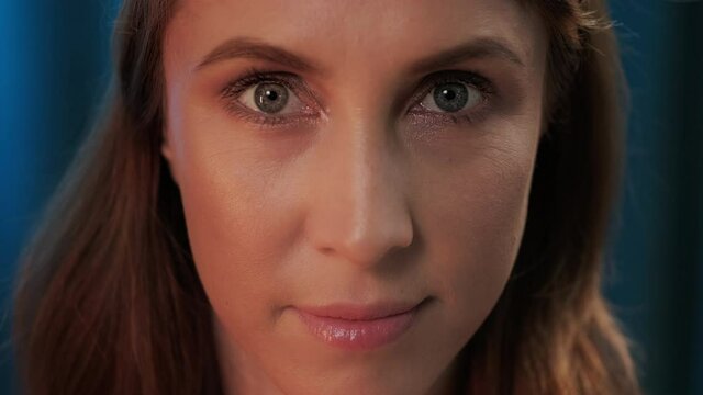 Portrait of the young woman opening her eyes and looking into the camera. Extreme close up studio portrait of the young adult woman