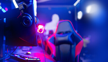 Professional gamers room with headphones microphone for cyber esports and video games on neon background of gaming monitor