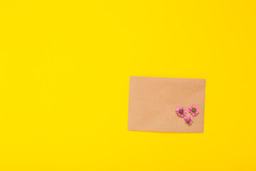 Sheet of craft paper and flowers on yellow background. Clean envelope. Handmade hobby material. Wrapping. Handicraft goods store. Recyclable. Card with copy space and free text place. Natural. Eco