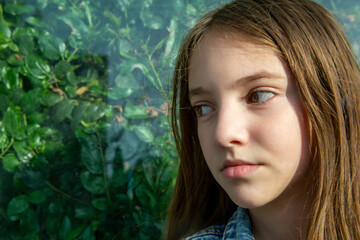 portrait of a teenage girl against a background of green foliage