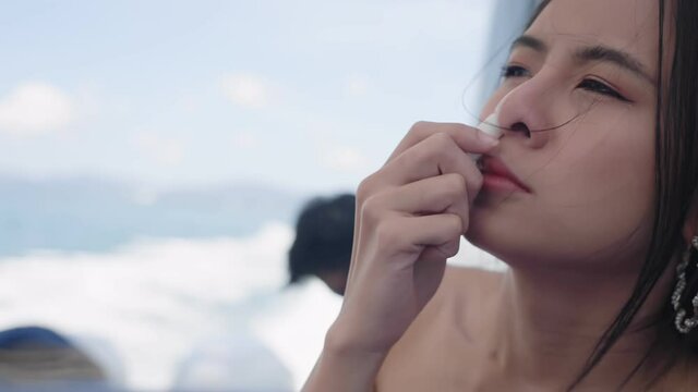 Asian young woman using inhaler healing herself from sea sick symptoms, sickness during travel, female feeling dizzy on speed boat, headache or nausea. Fear of travel or illness body discomfort