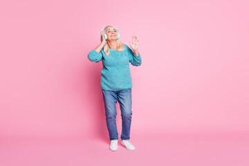 Full length photo of old lady dance have fun wear blue pullover jeans earphones footwear isolated pink pastel color background