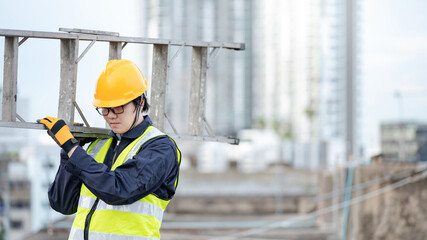 Asian maintenance worker man with safety helmet and reflective suit carrying aluminium step ladder at construction site. Civil engineering, Architecture builder and building service concepts © zephyr_p