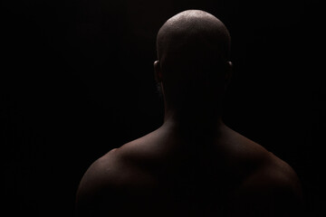 dark key photo from the back  of a black shirtless man - 405082877