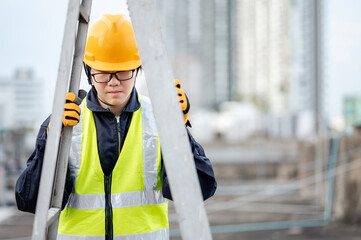Asian maintenance worker man with safety helmet and reflective suit adjusting aluminium step ladder...