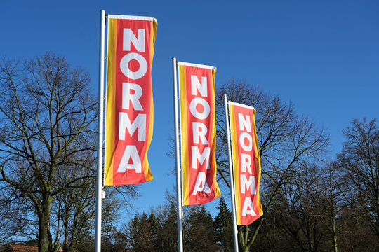 Ratzeburg, Germany, January 12, 2021: Advertising flags with the logo of the supermarket Norma against a blue sky, widespread food discounter with stores in Germany and Europe.