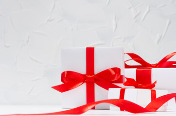 Classic elegant festive congratulation background with white gift boxes with red bow, curl ribbon in white interior, copy space, closeup.