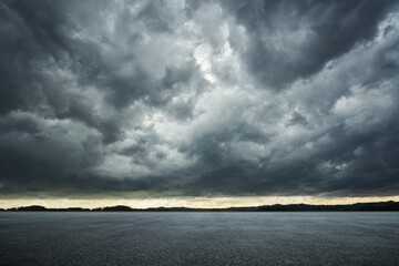 Empty asphalt ground floor with dramatic windstorm clouds sky .