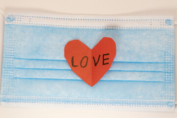 red heart on a mask on valentine's day on a white isolated background. heart surgical mask with place for inscription, mock up, copy space