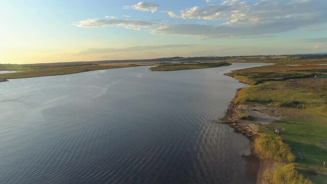 Aerilal rise high above Snowy River estuary and lone fishing boat at sunset. Marlo, Australia