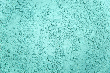 small and large drops of condensation on frosted colored glass