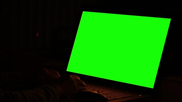 Woman working at night in front of green monitors