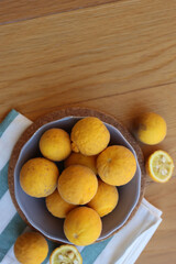 Trifoliate yellow fruits on wooden table. Many Poncirus trifoliata fruits in a bowl