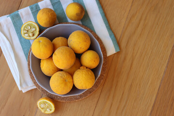Trifoliate yellow fruits on wooden table. Many Poncirus trifoliata fruits in a bowl