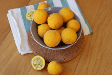 Trifoliate yellow fruits on wooden table. Many Poncirus trifoliata fruits in a bowl