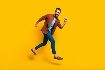 Fototapeta na wymiar Full length body size photo of man running fast laughing happy jumping isolated on vibrant yellow color background