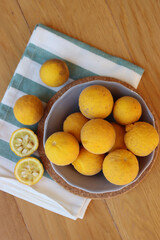 Trifoliate yellow fruits on wooden table. Many Poncirus trifoliata fruits in a bowl