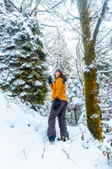 A Caucasian girl with a yellow jacket in the snowy forest of the Artikutza natural park in Oiartzun...