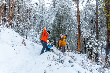 Three young people enjoying winter in the snowy forest of the Artikutza natural park in Oiartzun...