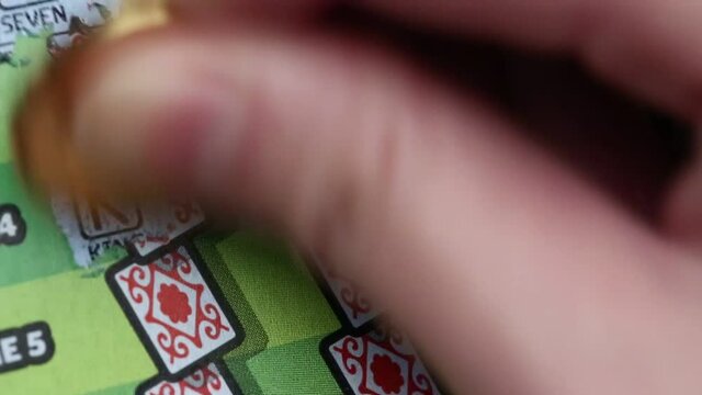 Close up woman scratching lottery ticket