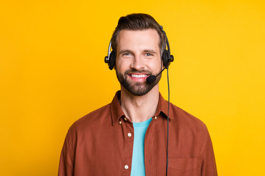 Photo portrait of call center employee smiling in earphones with microphone isolated on vivid yellow color background