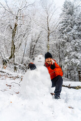 A young man joking with a snowman in the snowy forest of the Artikutza natural park in oiartzun...