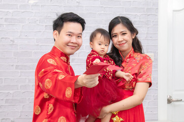 Selective focus on happy father provide envelop angpao for kid baby on Chinese New year Traditional, Chinese family spent time together, father play with his daughter and beautiful mother at home